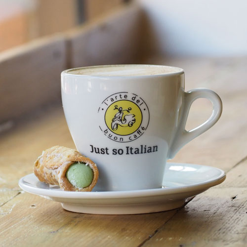Side photo of a Just so Italian coffee cup with a crispy Italian pastry on the side