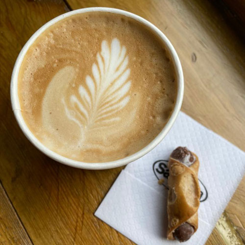 Freshly made coffee next to a crisp chocolate filled Sicilian Cannoli (Italian pastry)